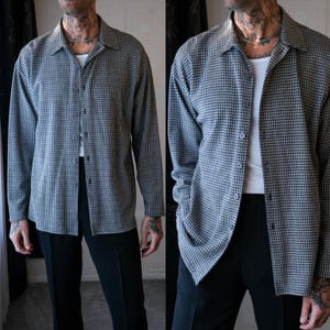 Op de afbeelding: Een zwart-wit geruit overhemd met lange mouwen, een kraag en een knoopsluiting. Het overhemd wordt gedragen met een zwarte broek. De outfit is een slimme, casual stijl.