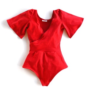 May include: A red bodysuit with short, flared sleeves and a wrap-style neckline.