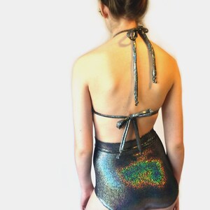 May include: A high-waisted, iridescent, silver and black swimsuit bottom with a halter top. The halter top is tied at the back of the neck.