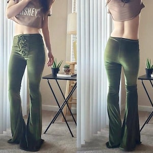 May include: A pair of green velvet bell bottom pants with a lace-up detail at the front. The pants are fitted through the hips and thighs and flare out at the bottom.