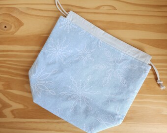 Medium blue and white snowflake project bag for knitting, crochet, or embroidery with drawstring and pockets; craft organization