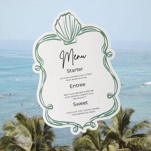 May include: A white menu card with a green shell-shaped border and decorative scrollwork. The text reads Menu, Starter, Ahi Tuna, Avocado Chilli Citrus Fruit, Black Olive Oil, Entree, Beef Fillet, Braised Short Rib, Duck, Smoked Carrots, Kale and Walnuts, Sweet, Chocolate Tart, Coffee Caramel, Mascarpone Ice Cream.