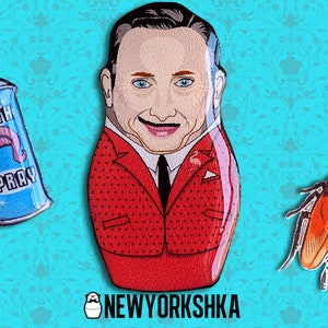 May include: A whimsical design featuring a Russian nesting doll with a smiling face, a red suit, and a black tie. Accompanying it are a blue "Filth Spray" can and a cartoon cockroach. The background is a teal floral pattern.