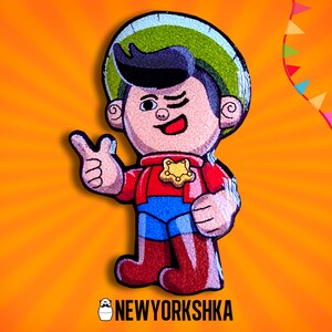 Pode incluir: Ilustração de desenho animado de um personagem de cowboy piscando, usando um chapéu verde e azul, camisa vermelha, calças azuis e botas marrons. O personagem está fazendo um gesto de polegar para cima. O fundo é laranja com linhas radiais e uma faixa de triângulos coloridos. O texto "NEWYORKSHKA" está na parte inferior.