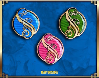 May include: Three decorative oval-shaped pins with a gold-colored filigree design. Each pin features a different color: blue, green, and pink. The background is a deep blue with gold accents. The text "NEWYORKSHKA" is visible at the bottom.