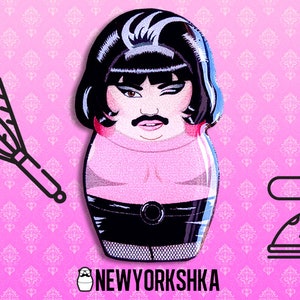 Puede incluir: Un fondo rosa con un patrón repetido de diseños florales blancos. La imagen presenta una ilustración de estilo caricatura de una persona con bigote y cabello negro, vestida con un atuendo negro. El texto "NEWYORKSHKA" está en la parte inferior.