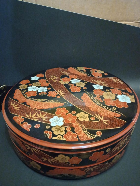 A Japanese Black Lacquer 4 Tier Bento Box with Gilt Floral Designs A Japanese Black Lacquer 4 Tier Bento Box with Gilt Floral Designs
