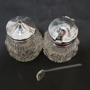 Small Pair of cut glass bottle condiments with a glass spoon. sugar and cream, powder cheese and spicy pepper shakers.