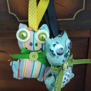 May include: Two handmade plush toys, one striped with green and yellow accents and the other with a green and white pattern, both with large googly eyes.