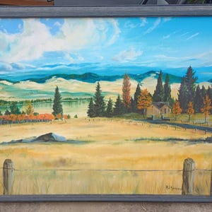 May include: A framed oil painting depicting a rural landscape with a small house, trees, and a lake in the distance. The sky is blue with white clouds. The painting is signed "Rd. Hummer" in the bottom right corner.