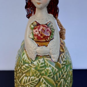 stonewear bell girl figurine holding a bouquet of red flowers,  stonewear. ceramic joy bell.