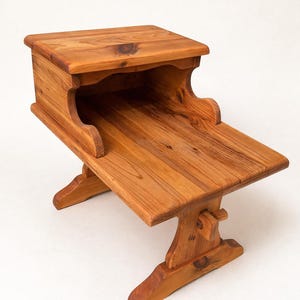 May include: A handcrafted wooden side table with a natural finish. The table features a rectangular top, a lower shelf, and a trestle base. The wood grain is visible, and the table is approximately 76 cm long.