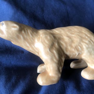 Peut inclure: Une figurine en céramique d'un ours brun debout sur ses quatre pattes. L'ours a une surface texturée qui ressemble à de la fourrure.