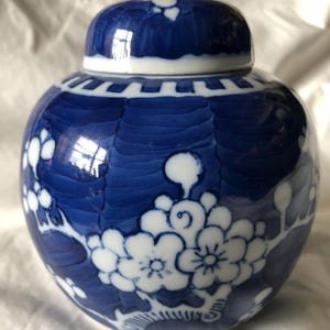 May include: A blue and white porcelain ginger jar with a floral design. The jar has a lid and is decorated with white flowers on a blue background.