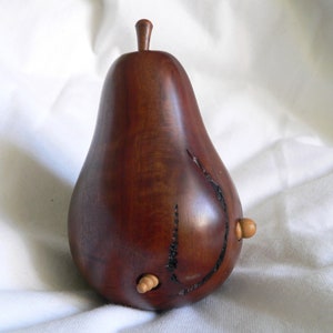 Può includere: Una scultura in legno a forma di pera con una finitura marrone scuro e due piccoli pomelli in legno sul lato.