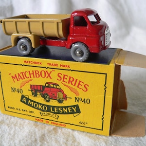May include: A red and tan toy dump truck with a Matchbox Series No. 40 box. The box is yellow with black text and a red and white logo that says "A Moko Lesney Product".