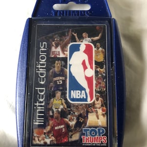 May include: A blue plastic case containing a deck of Top Trumps cards. The card design features NBA players and the NBA logo. The words "limited editions" and "Top Trumps" are visible on the case.