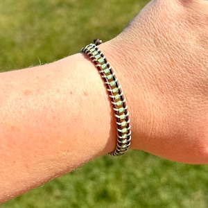 May include: A brown leather bracelet with a row of light green beads.