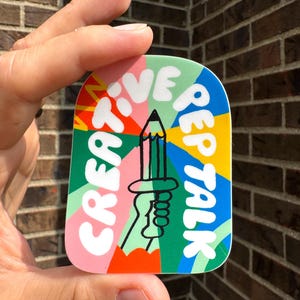 May include: A colourful sticker with the words "Create, Live, Rep, Talk" in white, with a pencil design. The sticker has a green, blue, yellow, pink, and orange colour scheme.