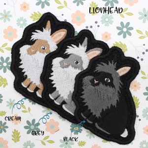 May include: Three embroidered lionhead rabbit patches in cream, grey, and black. The patches are on a white background with pink and green flowers.