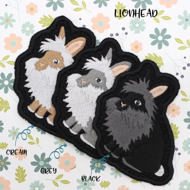 May include: Three embroidered lionhead rabbit patches in cream, grey, and black. The patches are on a white background with pink and green flowers.