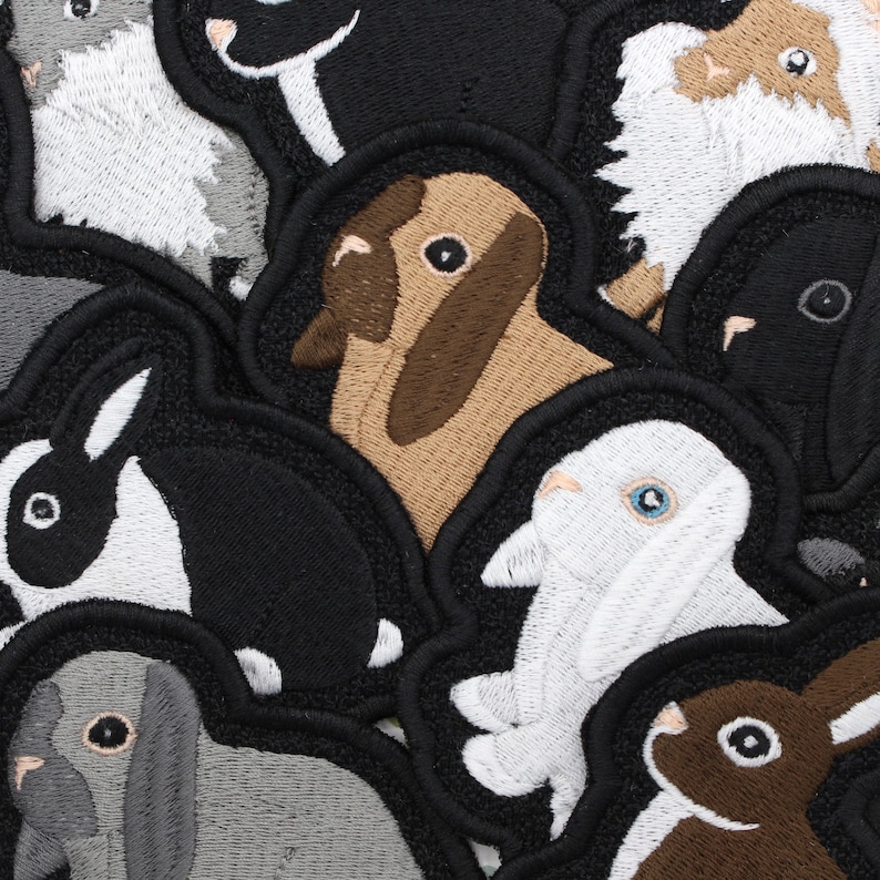 May include: A collection of embroidered patches featuring various animals, including rabbits, a dog, and a sheep. The patches are all different colors and have a variety of designs.