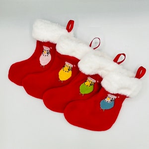May include: Four red Christmas stockings with white fur trim and embroidered images of colorful birds.
