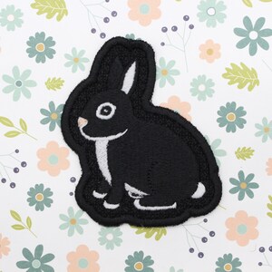 May include: Black embroidered iron-on patch of a rabbit with white accents.