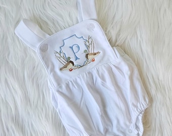 May include: White baby onesie with a blue and green embroidered design featuring a letter "P" and two ducks.