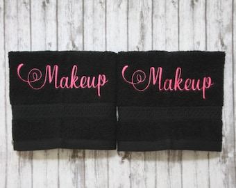 May include: Two black hand towels with the word "Makeup" embroidered in pink on each towel.