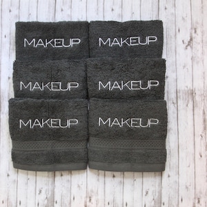 May include: Six dark gray towels with white embroidery that reads "MAKEUP" on each towel.