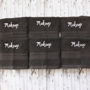 May include: Six dark gray hand towels with white embroidery that reads "makeup" on each towel.