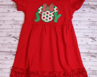 May include: Red short-sleeved dress with a ruffled hem. The dress features an embroidered green, white, and red Minnie Mouse head with a bow and the word "JOY" underneath.