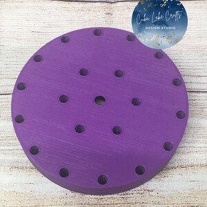 May include: Purple round cake stand with 20 holes for cupcakes. The stand is made of wood and has a smooth finish.