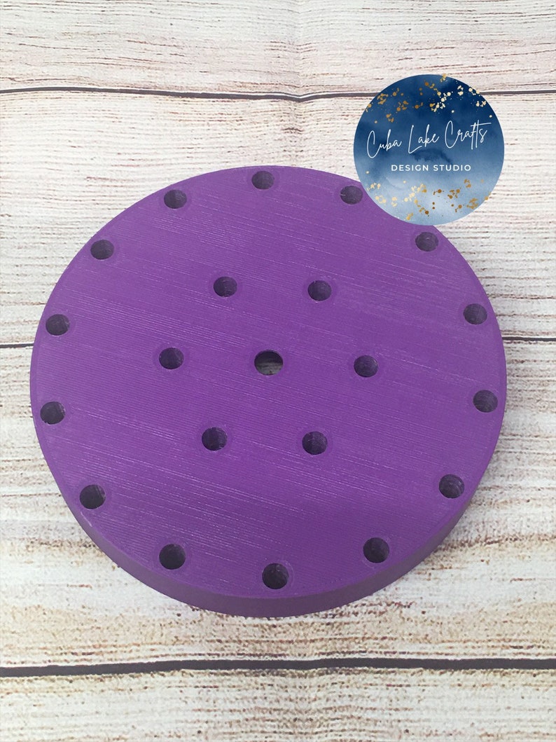 May include: Purple round cake stand with 20 holes for cupcakes. The stand is made of wood and has a smooth finish.