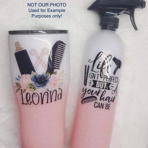 May include: Two pink glitter tumblers with a white ombre effect. One tumbler has a design of a pair of scissors, a hair comb, and flowers. The other tumbler has the text "Life isn't perfect but your hair can be".