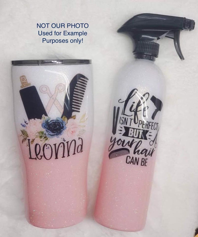 May include: Two pink glitter tumblers with a white ombre effect. One tumbler has a design of a pair of scissors, a hair comb, and flowers. The other tumbler has the text "Life isn't perfect but your hair can be".