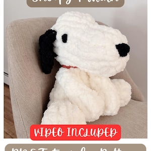 Pode incluir: Um boneco de pelúcia branco Snoopy com orelhas e olhos pretos e uma coleira vermelha está sentado em uma cadeira. A imagem inclui o texto "Snoopy Pattern", "Video Included" e "PDF Tutorial + Pattern".