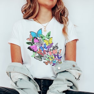 May include: A white t-shirt with a colorful butterfly design. The butterflies are arranged in a cluster and are in various shades of pink, blue, green, yellow, and orange.