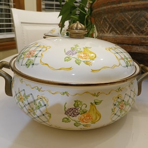 Könnte beinhalten: Eine weiße Keramik-Tasse mit schwarzem Henkel und dem Text "But First, Coffee" in fetter, schwarzer Schrift. Die Tasse steht vor einem verschwommenen Hintergrund, der eine gemütliche Umgebung suggeriert.