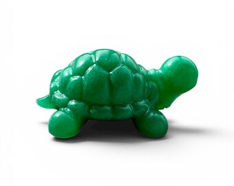 Peut inclure: Une petite figurine de tortue en vert émeraude massif avec une finition lisse et brillante. La tortue est représentée de profil, mettant en valeur une carapace détaillée avec des plaques segmentées, quatre pattes arrondies et une tête lisse.
