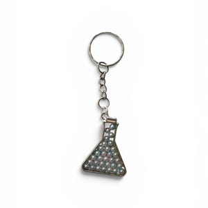 May include: A silver-toned metal keychain featuring a triangular Erlenmeyer flask charm. The flask is filled with numerous small, iridescent, light blue and white spherical beads that resemble tiny pearls, attached to a standard circular split ring.