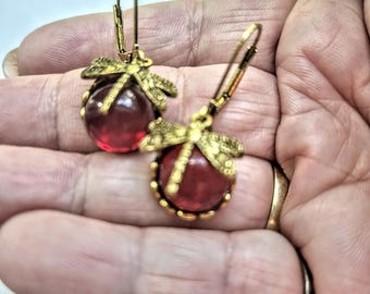 Brincos de libélula em tom dourado: cabochão vermelho rubi, fecho de alavanca.