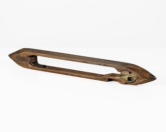 Peut inclure: Une navette en bois utilisée pour le tissage, avec une extrémité pointue et une petite pièce métallique sur le côté.