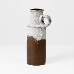 May include: A brown and white ceramic vase with a handle. The vase has a textured glaze and a speckled finish.