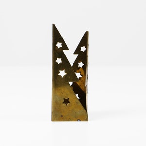 May include: A gold metal candle holder shaped like two overlapping triangles with star cutouts.
