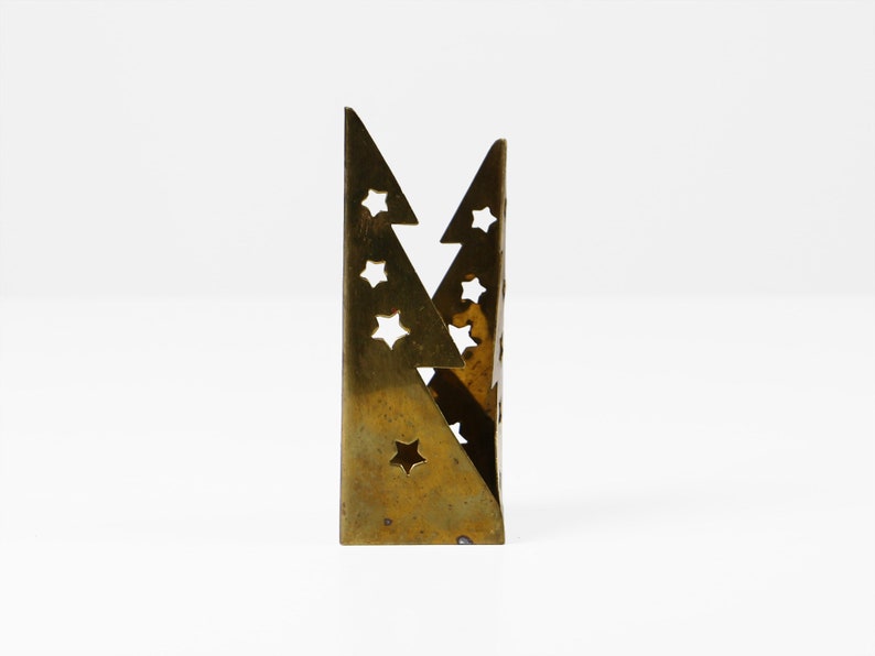 May include: A gold metal candle holder shaped like two overlapping triangles with star cutouts.