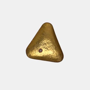Könnte beinhalten: Ein goldfarbenes, dreieckiges Objekt mit strukturierter Oberfläche und einem kleinen, dunklen Detail in der Mitte. Das Objekt hat abgerundete Kanten und einen metallischen Glanz.