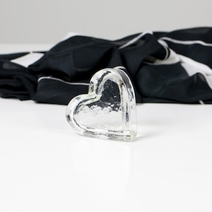 May include: A clear glass heart-shaped paperweight with a textured surface.