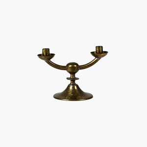 Peut inclure: Un bougeoir en métal doré avec deux bras et une base ronde. Le bougeoir est conçu pour accueillir deux bougies.
